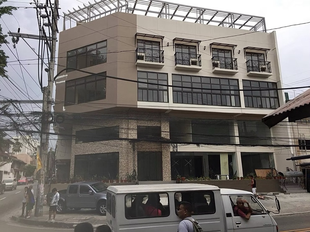Completed commercial building: a glazed office frontage with balconies and a concrete frame above street level.