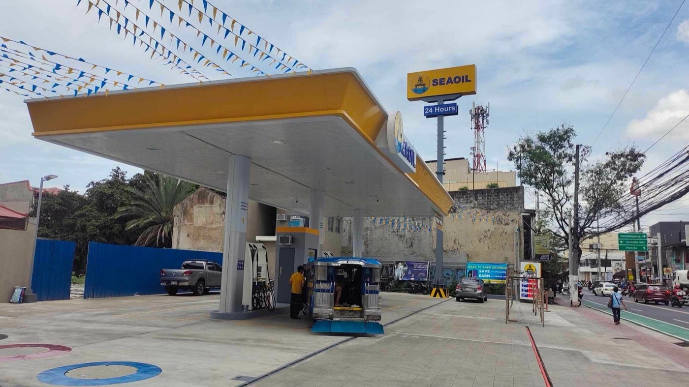 Completed SEAOIL service station on JP Rizal in Makati: a wide yellow and white canopy over the dispenser islands, with a jeepney refuelling and the forecourt open to traffic.
