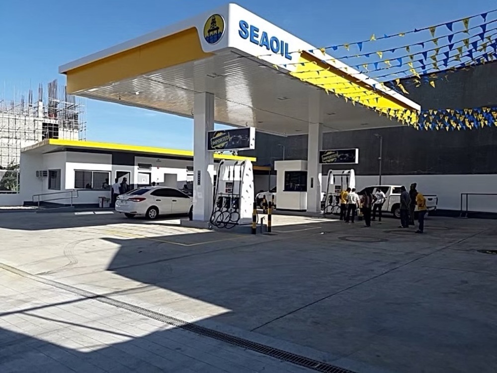 Completed station: canopy over the pumps, with staff on the forecourt and a car being served.