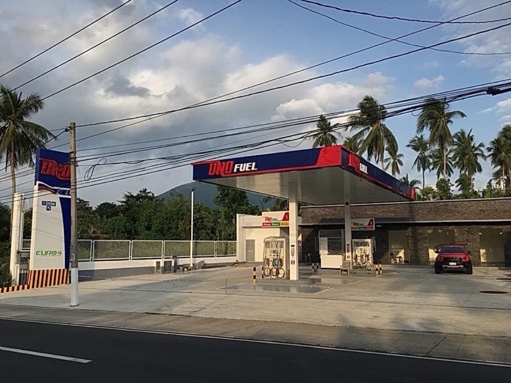 Completed station: canopy and dispenser island with the pylon sign, palm trees behind.