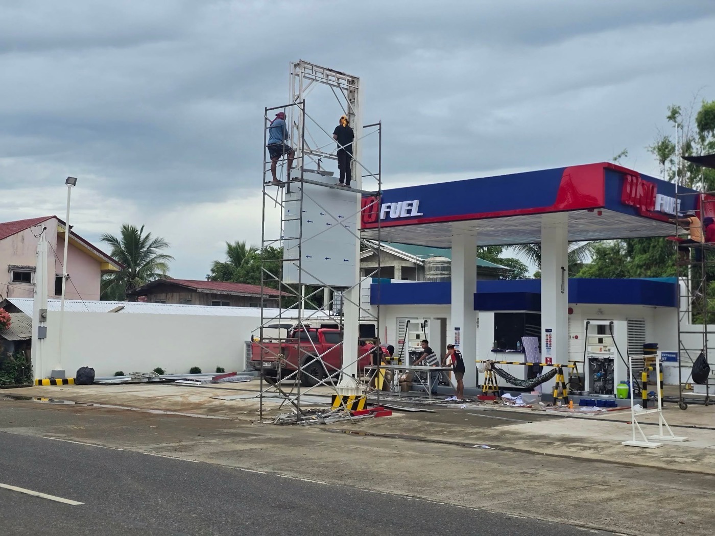 UNO Fuel service station under construction in Camalaniugan, Aparri: workers on scaffolding erecting the pylon sign above the newly built canopy.